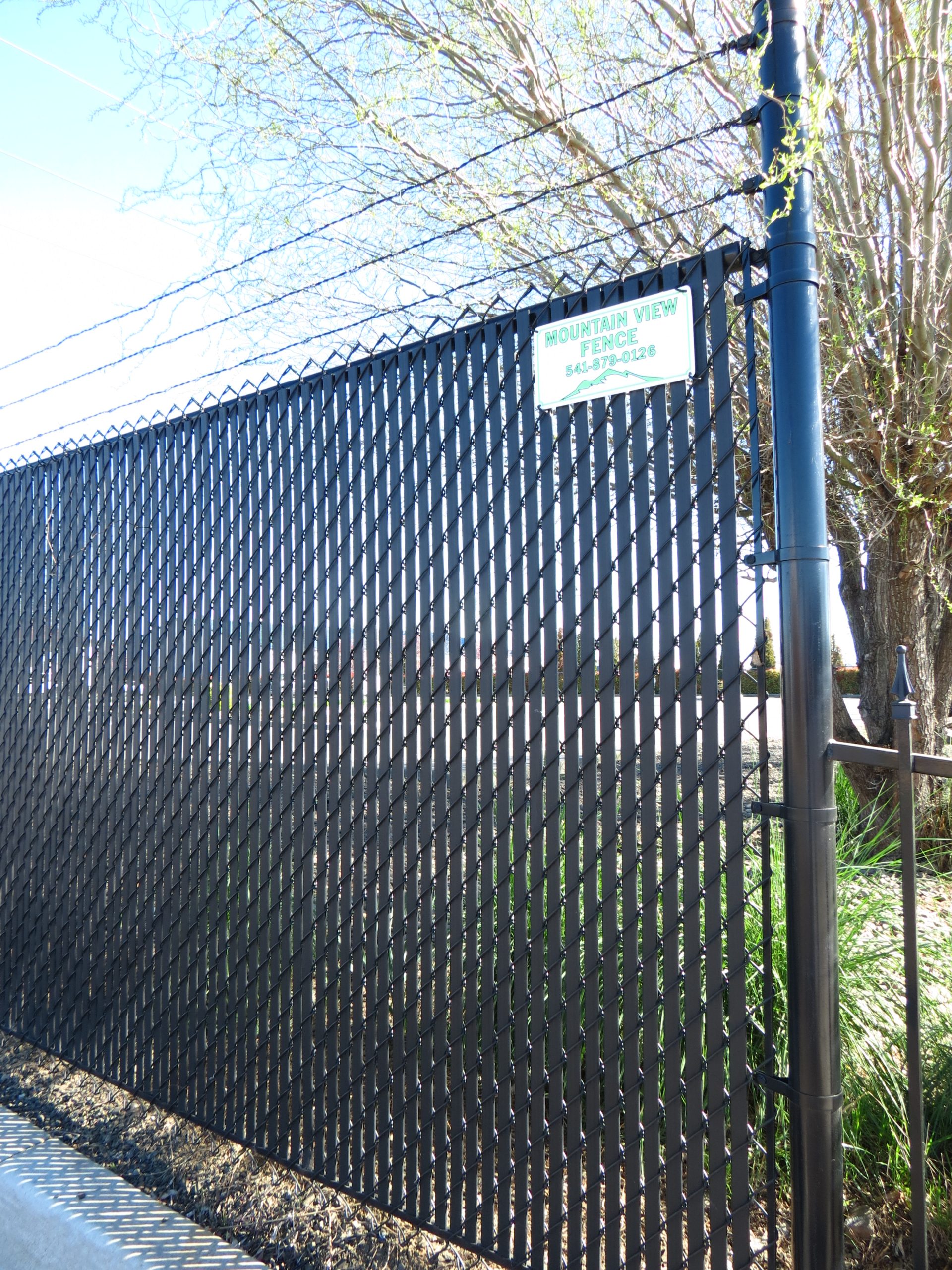 Six foot all black Chain Link fence with privacy slats at a Medford commercial property